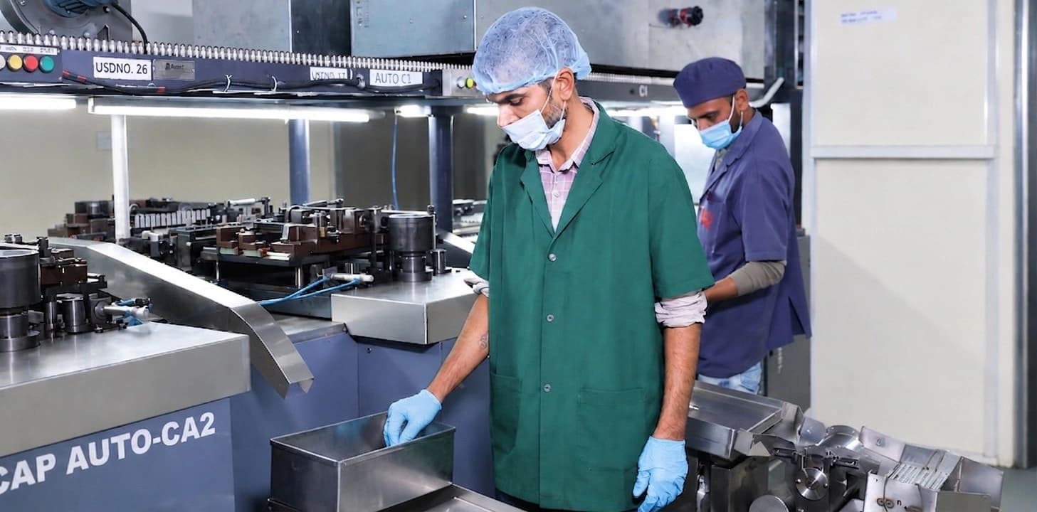 Technicians operating capsule manufacturing machinery inside the Saviour Caps facility