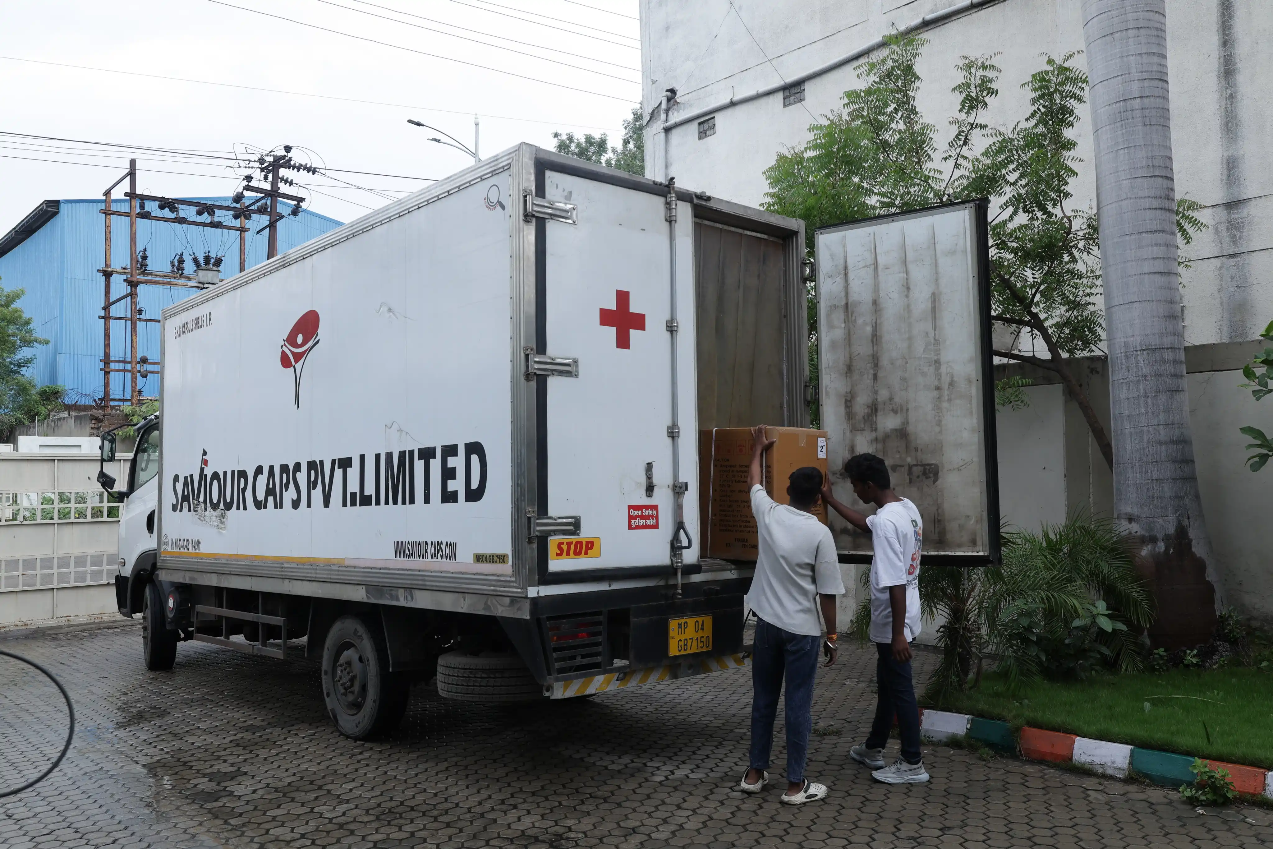 Workers loading packaged capsule cartons into a delivery vehicle